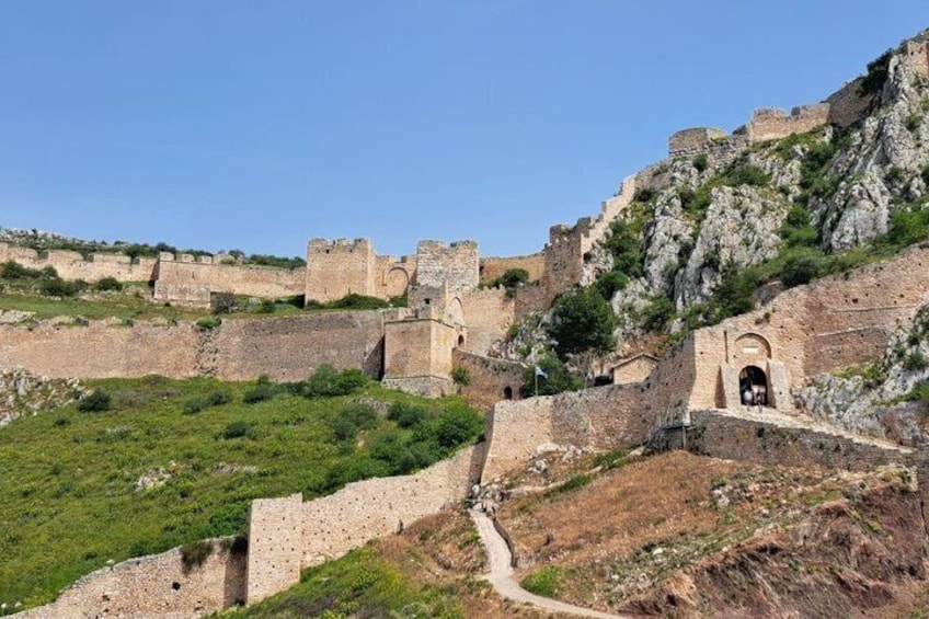 A historical fortification with walls and towers, a clear sky, and a path leading through the ruins. 4