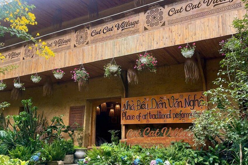 A wooden building with hanging flower baskets and a sign that reads 'Cat Cat Village.' 4
