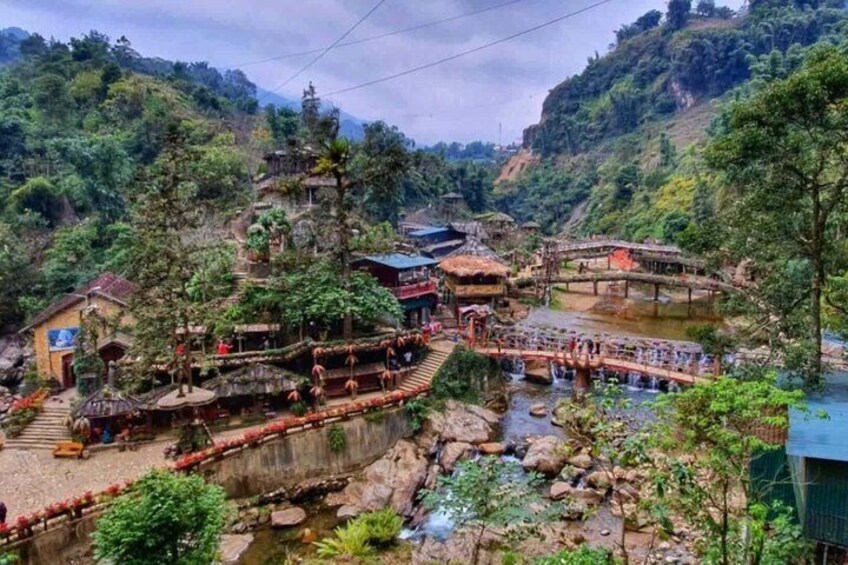 A traditional village with a river, wooden bridges, and terraced structures. 1