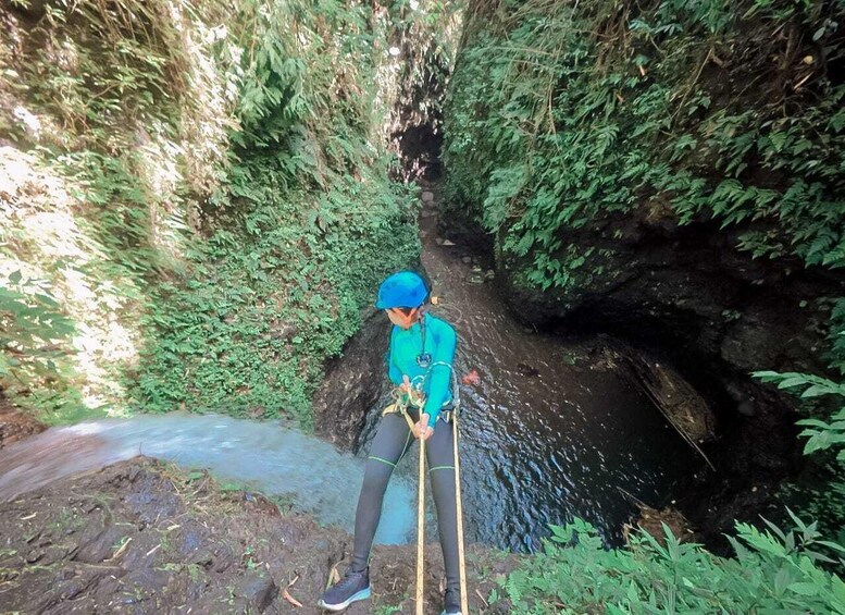 A person in blue gear climbing a rocky path with a rope. 1