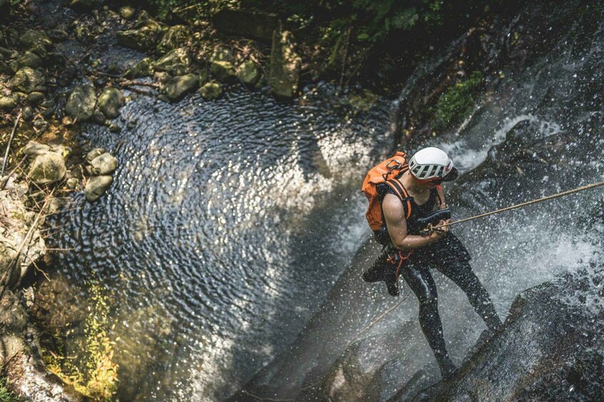 A person rappelling down a rocky waterfall. 3