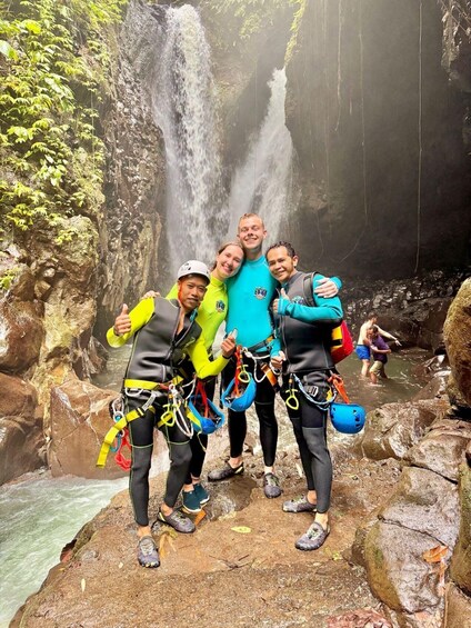 A group of people in a forested area with a waterfall. 4