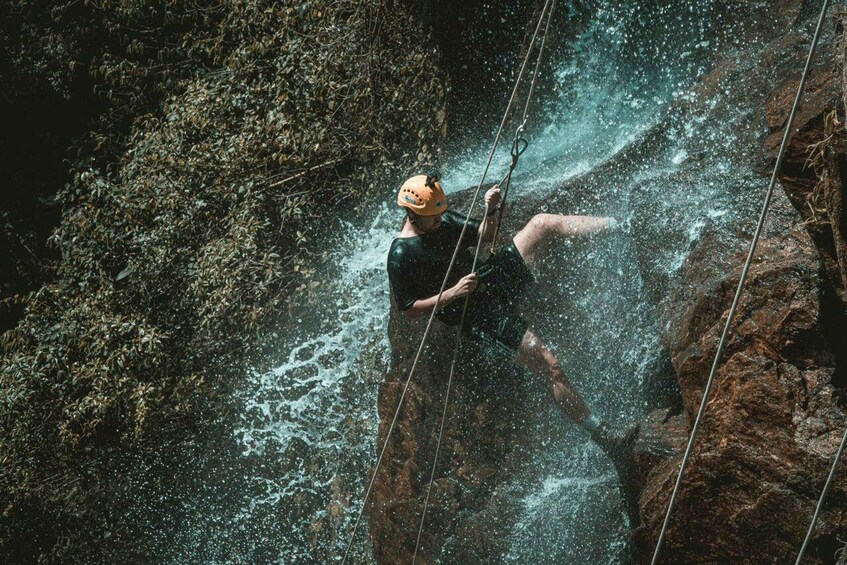 A person rappelling down a rocky cliff with water cascading around them. 5
