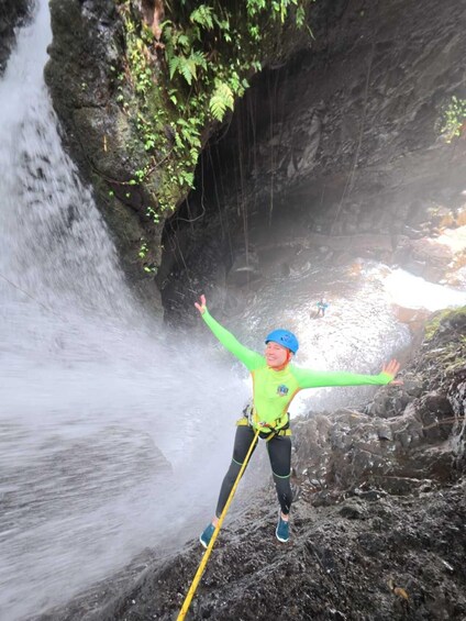 A person bungee jumping from a rocky cliff with a waterfall in the background. 2