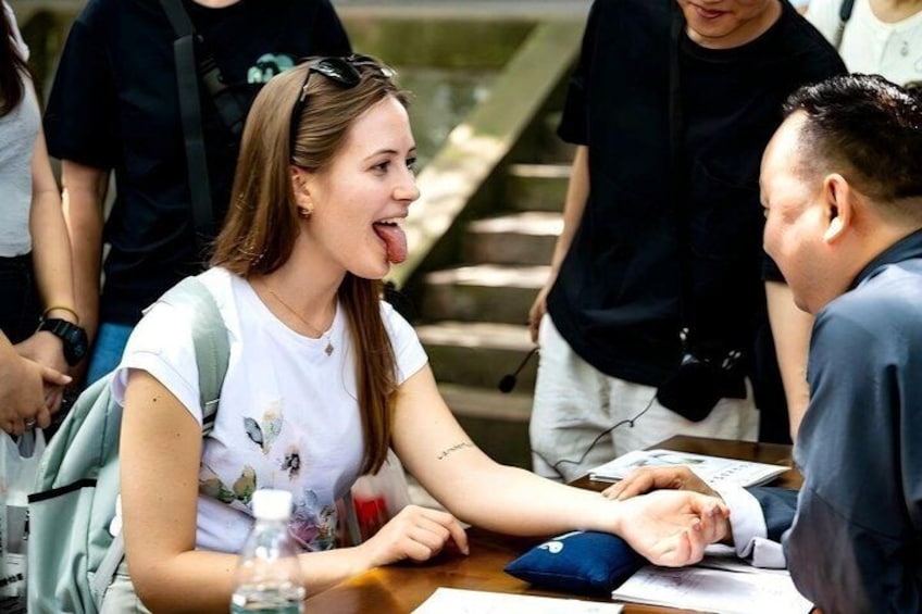 A person sitting at a table with a water bottle and papers, in a public indoor space with stairs in the background. 1