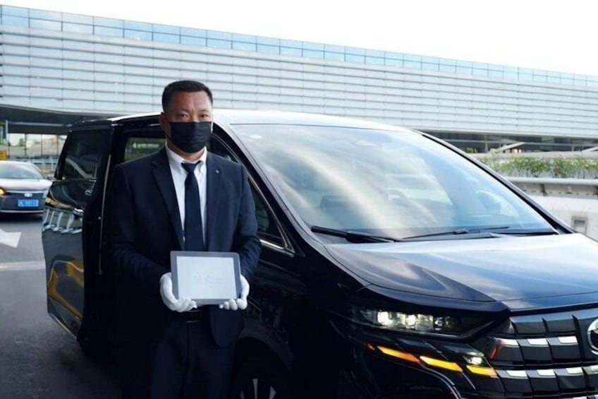 A person in a suit standing next to a black van with a laptop. 2