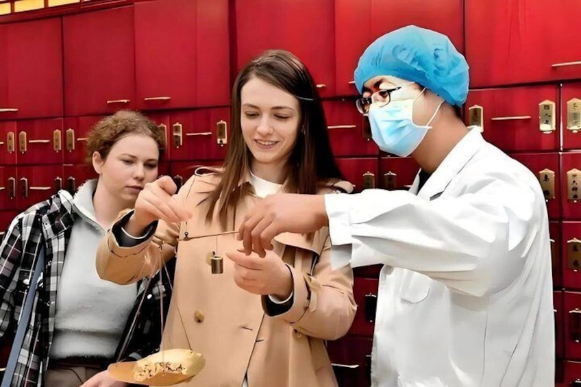 Three people in a red locker room, one wearing a lab coat and a blue hairnet, another in a beige coat, and the third in a plaid shirt, examining a small object. 4