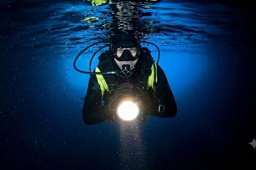 A person underwater with a flashlight. 1