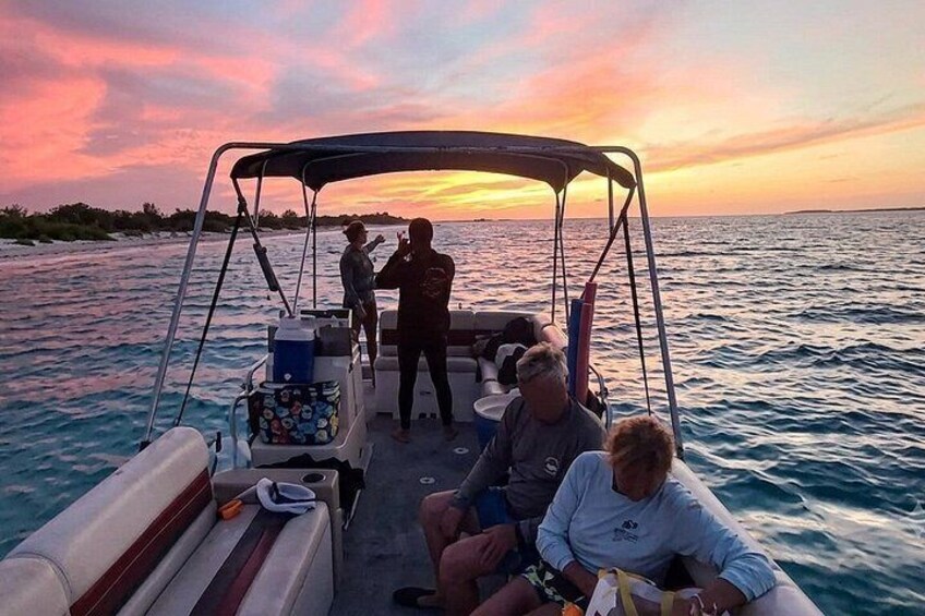 A boat with people on a body of water during sunset. 2