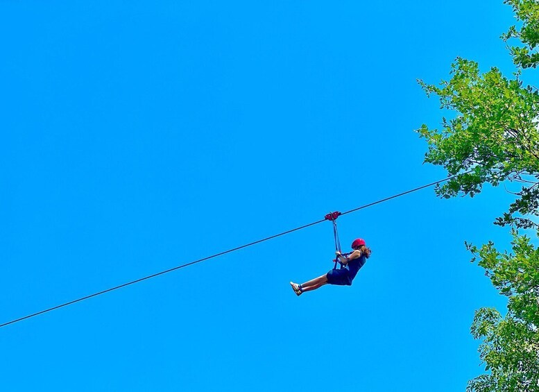 A person ziplining through a clear blue sky. 1