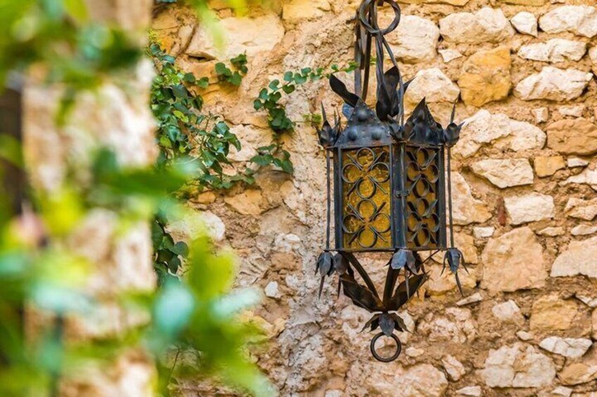 A wrought iron lantern hanging on a stone wall with ivy growing around it. 5