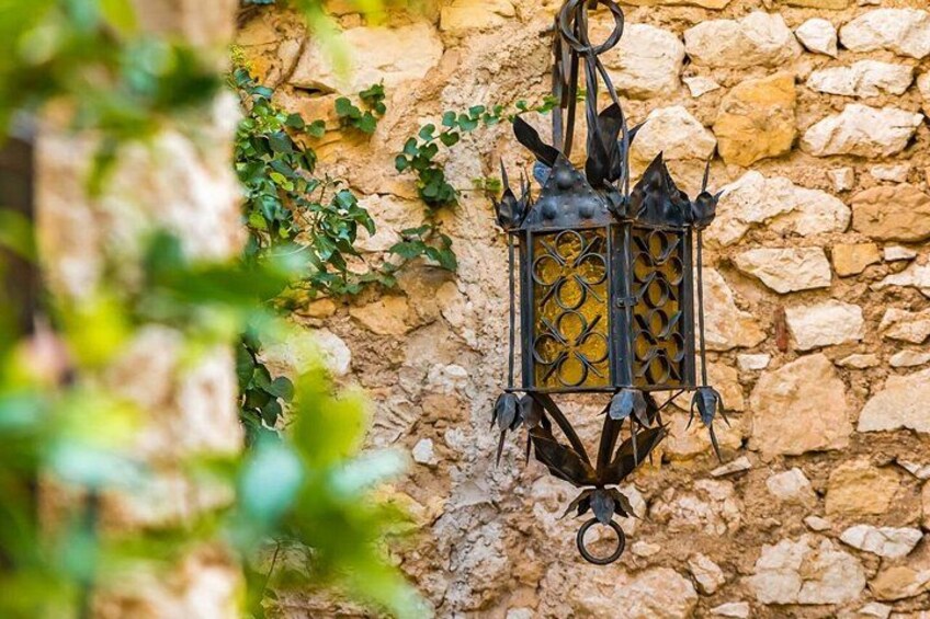 A wrought iron lantern hanging on a stone wall with ivy growing around it. 5