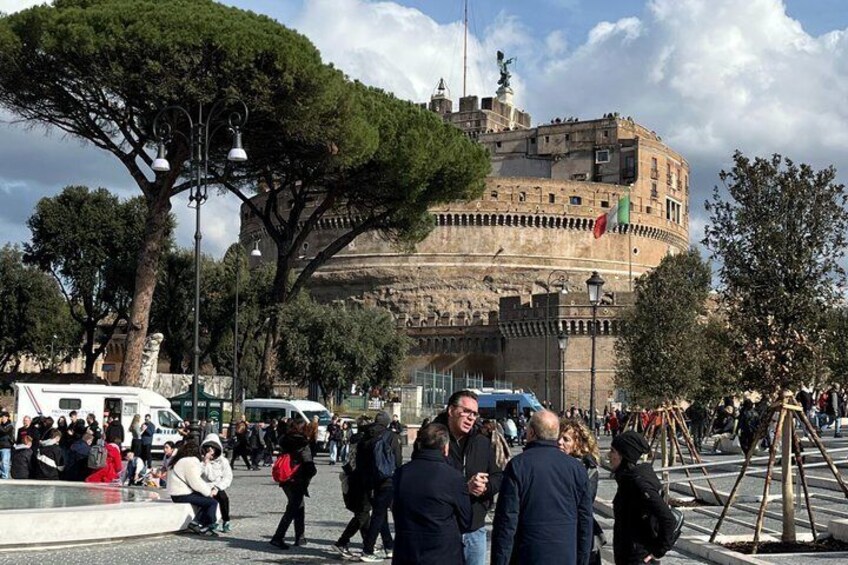 A crowded square with a historic building featuring a prominent tower and flag. 3