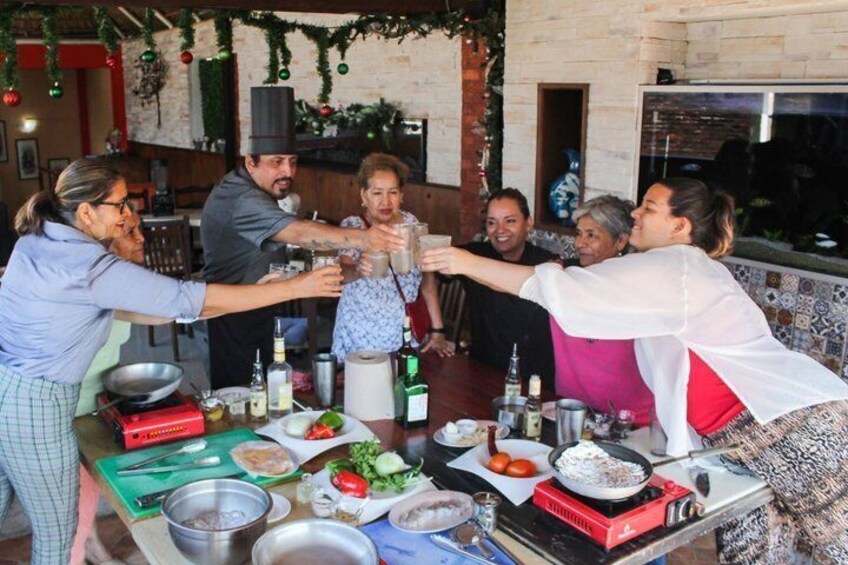 A group of people toasting at a table with food and drinks. 1