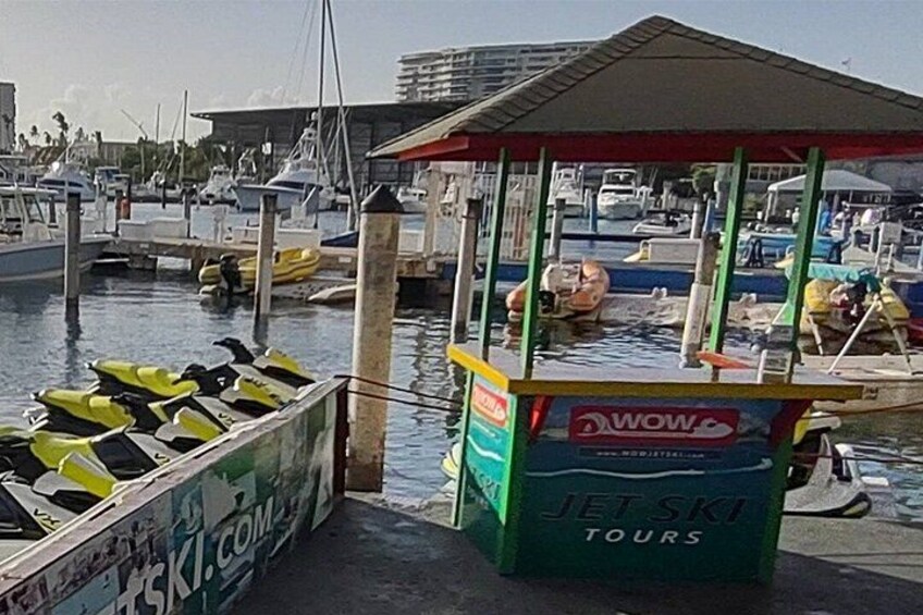 A marina with boats docked, a jet ski rental booth, and a small covered area. 2