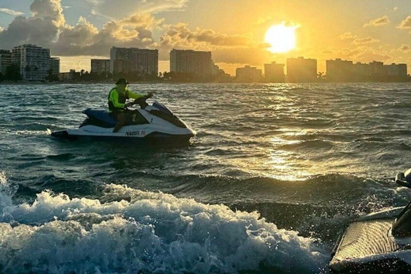 A person jet skiing on water with a city skyline in the background during sunset. 4