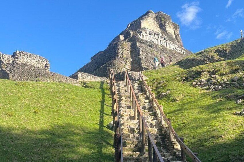 A stone staircase leading to a pyramid-like structure on a grassy hill. 3