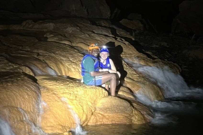 Two people sitting on a rock formation near a flowing stream. 5