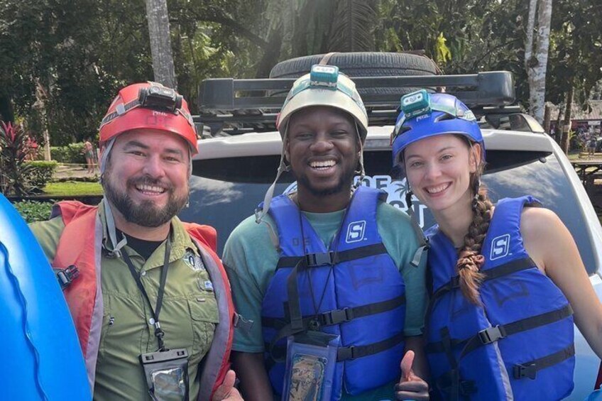 Three people wearing life jackets and helmets, standing in front of a vehicle. 4