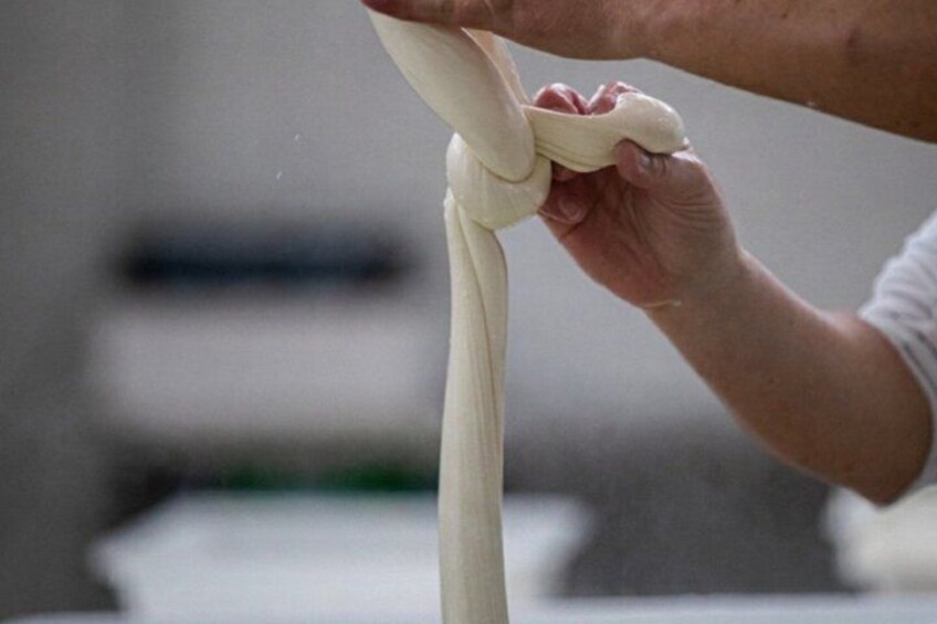 A person tying a knot with a piece of dough. 4