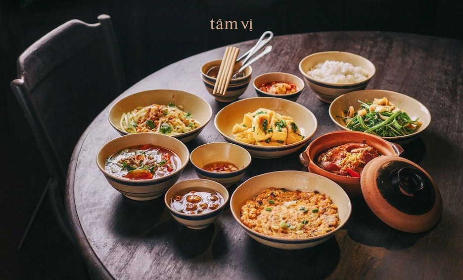 A variety of Asian dishes on a wooden table with chopsticks and bowls. 1