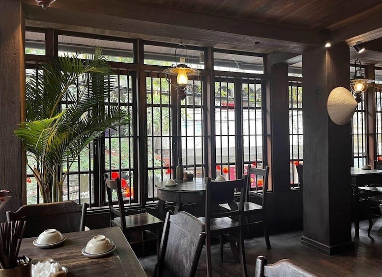 An indoor dining area with large windows, wooden tables, chairs, and hanging light fixtures. 4