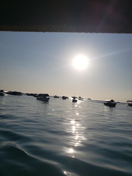 A calm sea with boats and the sun reflecting on the water. 2