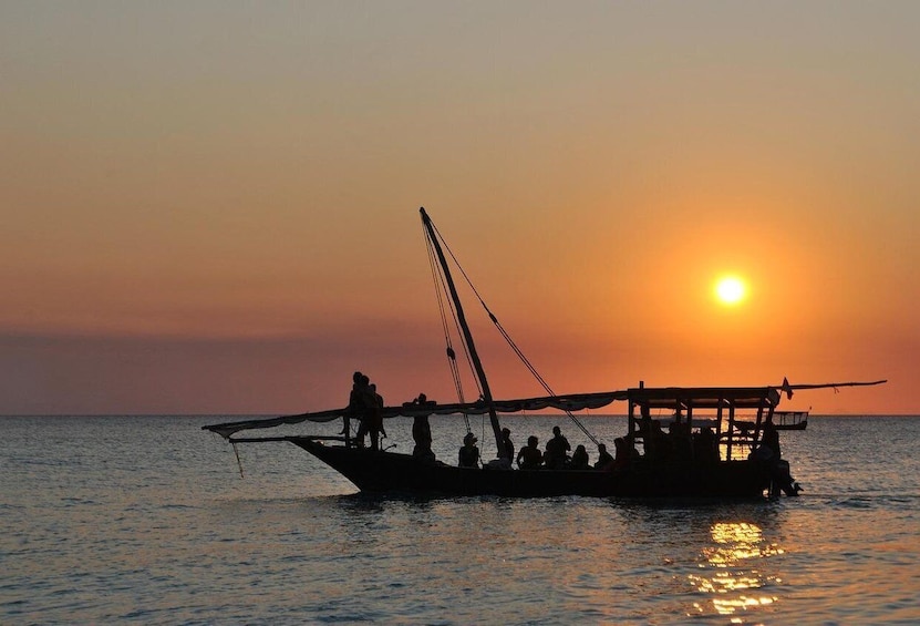 A traditional boat with people on it during sunset. 1