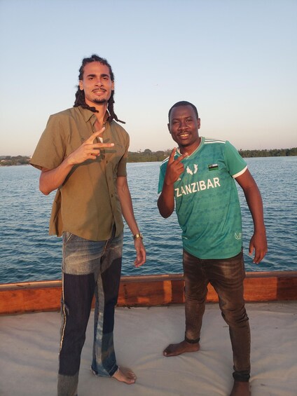 Two individuals standing on a boat with a body of water and a distant shoreline in the background. 5