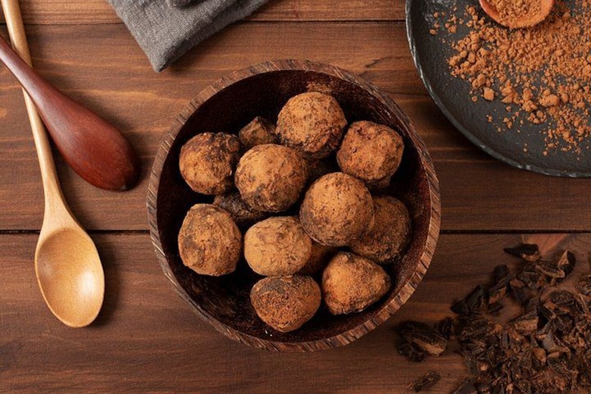 A wooden bowl filled with round, brownish objects on a wooden surface. 2