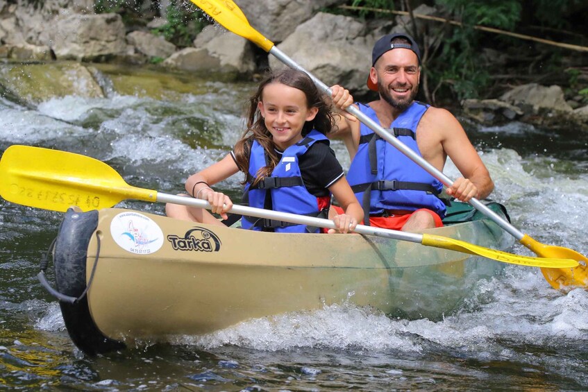 Two people in a yellow inflatable raft with paddles, navigating a river. 2
