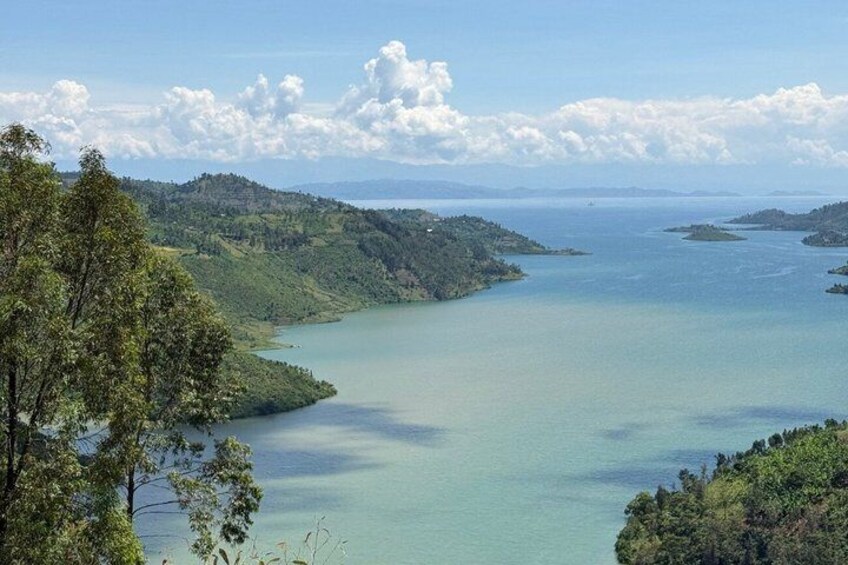 A coastal landscape with a calm sea, green hills, and a clear sky. 1