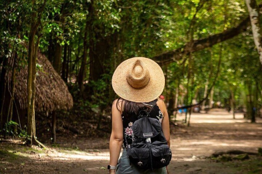 A person walking on a forest path with a straw hat and a backpack. 1