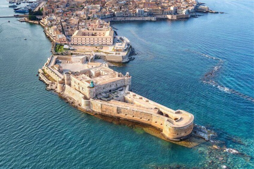 An aerial view of a coastal city with a prominent fortified structure and a harbor. 5