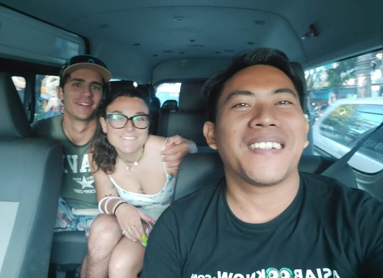 Tres personas en un coche con un paisaje urbano de fondo. 3