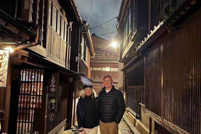 A narrow alleyway with wooden buildings, a sign with Japanese characters, and a person in a black jacket. 2