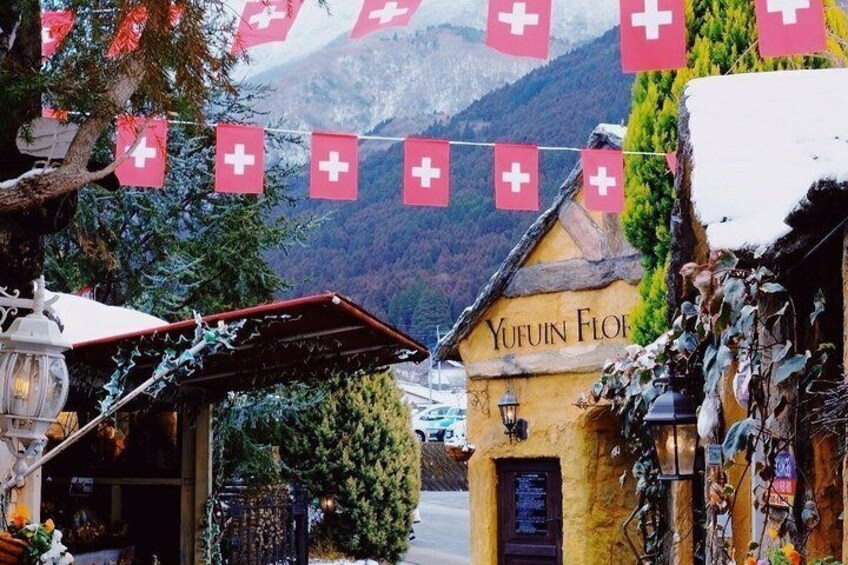 A Swiss village with a building named 'Yufuin Flour' and a mountain backdrop. 3