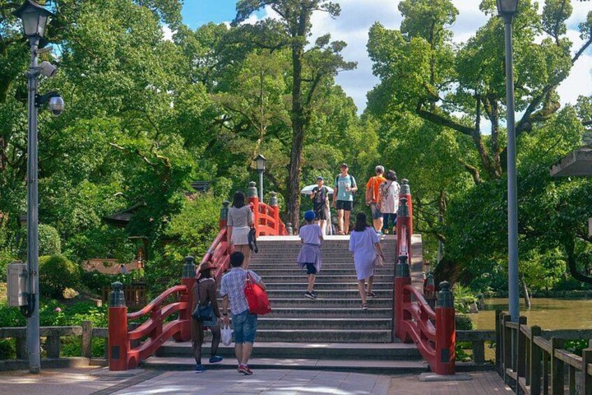 A group of people ascending a set of red stairs in a park with lush green trees and a clear sky. 1