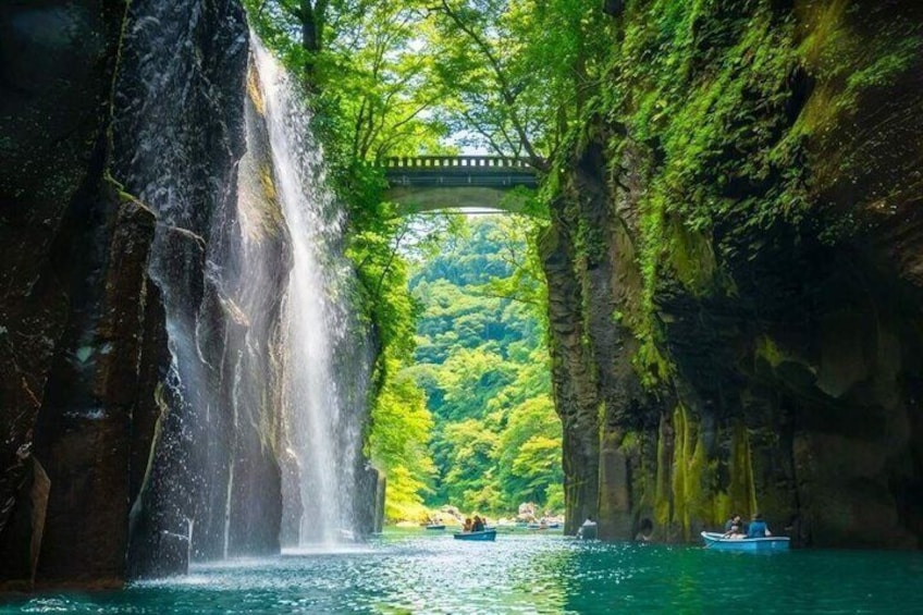 A waterfall, a bridge, and a forested area with boats. 1
