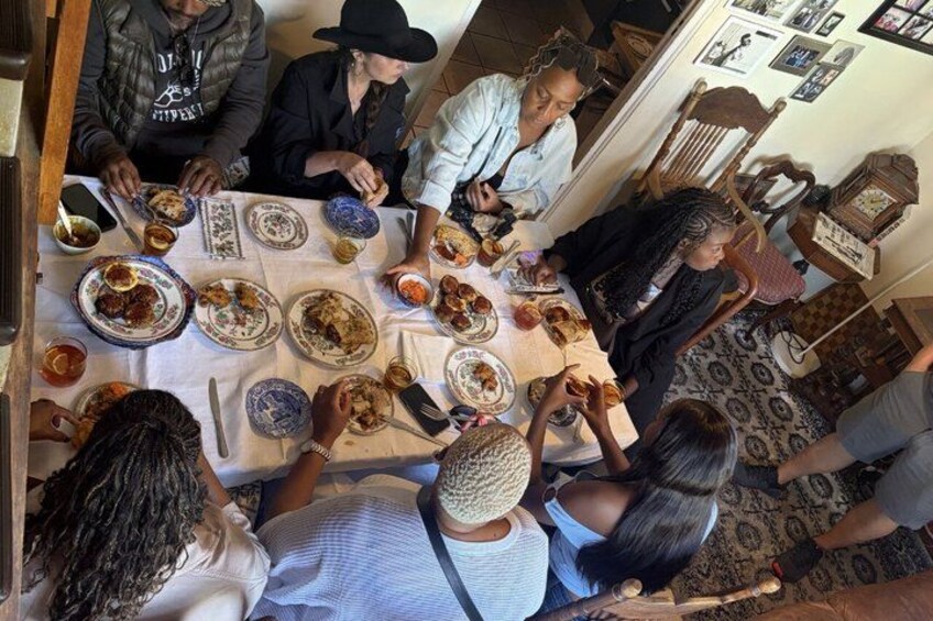 Un gruppo di persone seduto attorno a un tavolo, traendo spunti dalla conversazione mentre gustano del cibo. 1