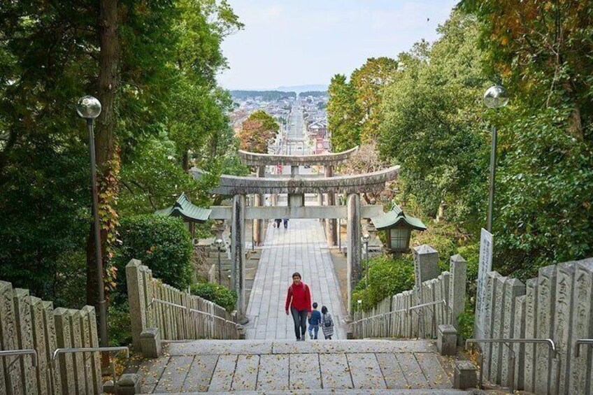 A stone staircase leading to a traditional Japanese gate with a view of a city in the distance. 1