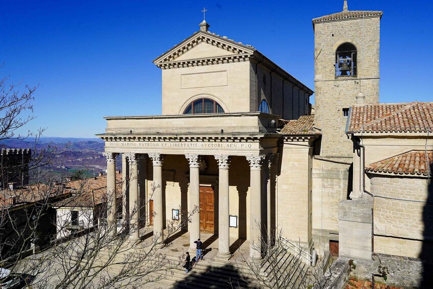 A church with a bell tower and columns, overlooking a valley. 5