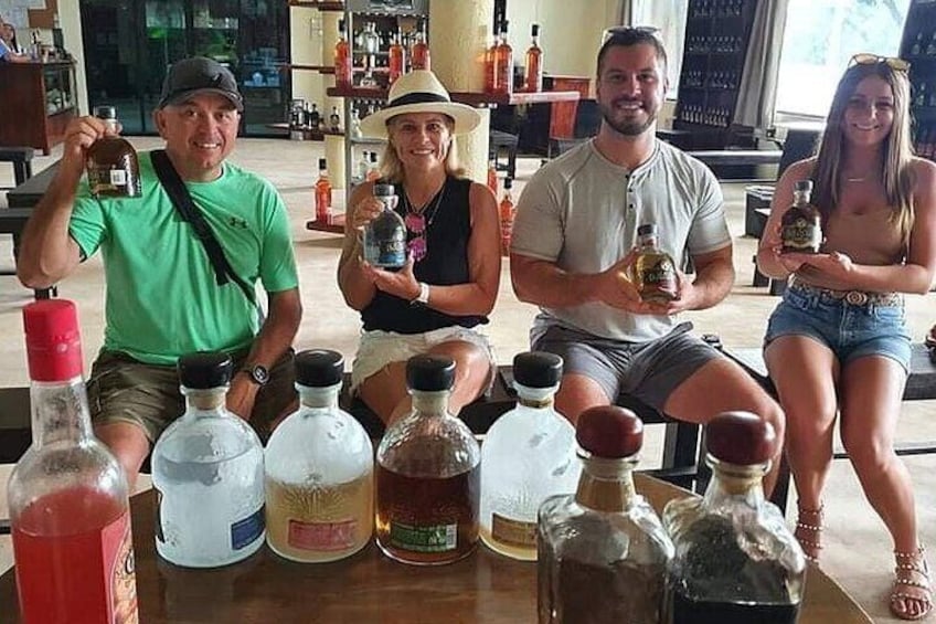 A group of people sitting at a table with various bottles of liquor. 1