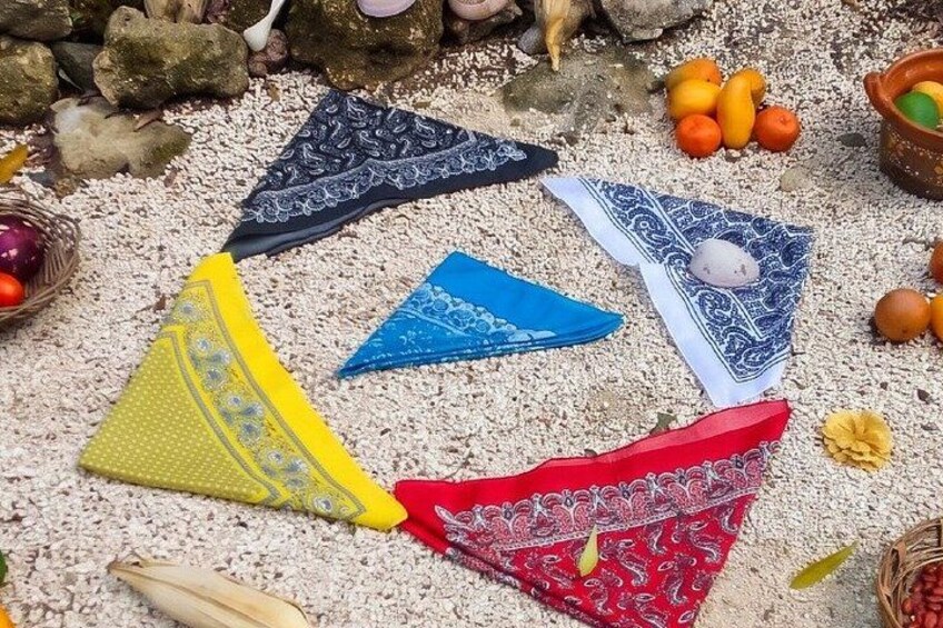 Bunte Bandanas, eine Korb mit Orangen und eine Schale mit Obst auf sandigem Untergrund. 5