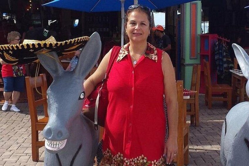 Eine Person steht neben einer Esel-Statue mit Sombrero. 2