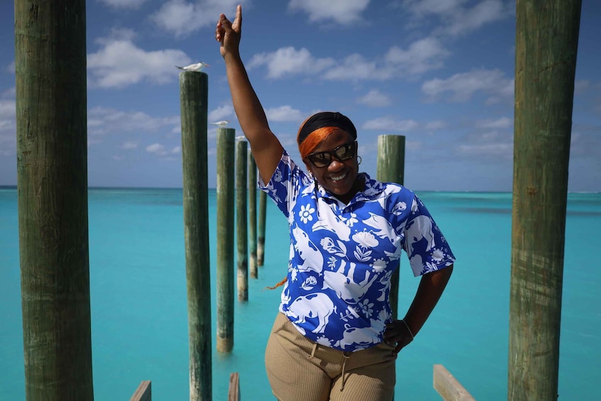 A person standing on a wooden pier with turquoise water in the background. 5