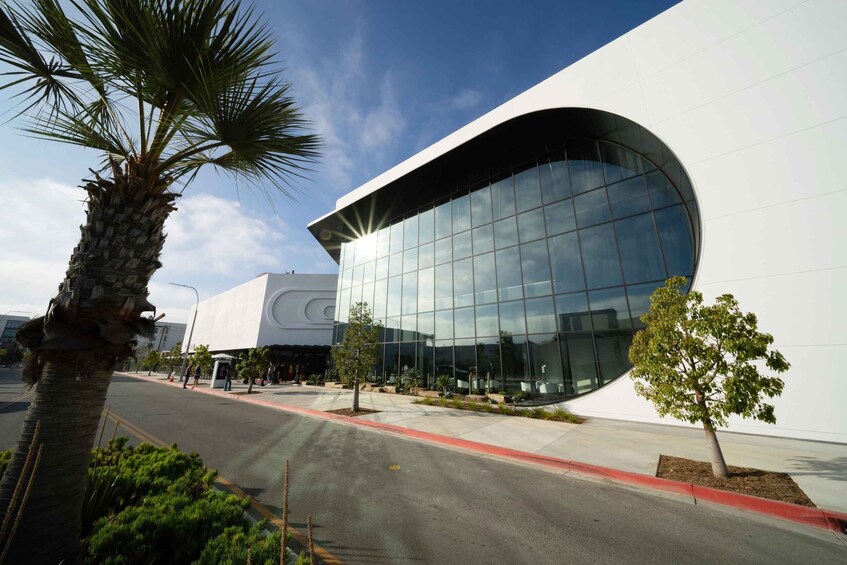 A modern building with a curved glass facade, palm trees, and a clear blue sky. 3