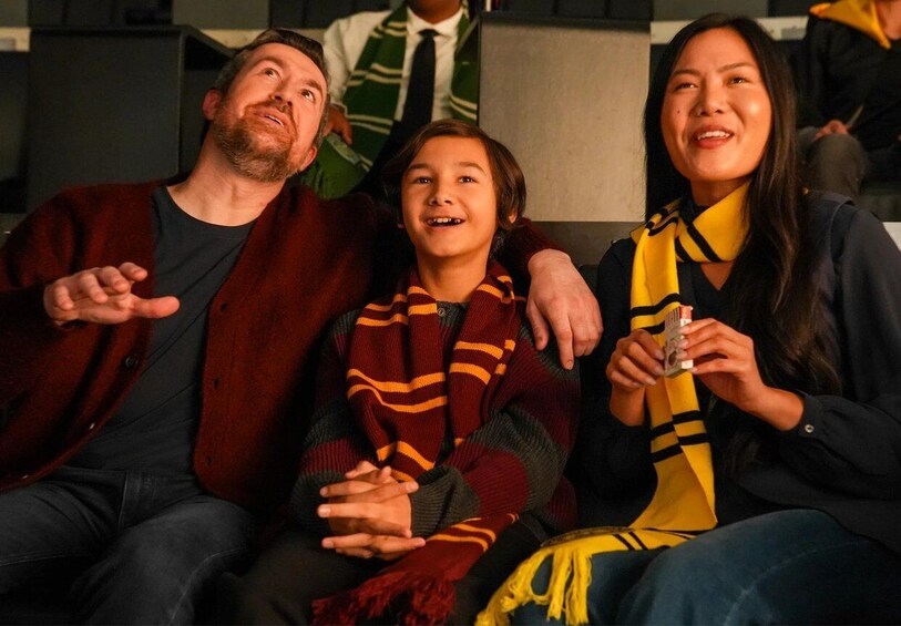 Three people sitting closely together, one holding a drink. 5