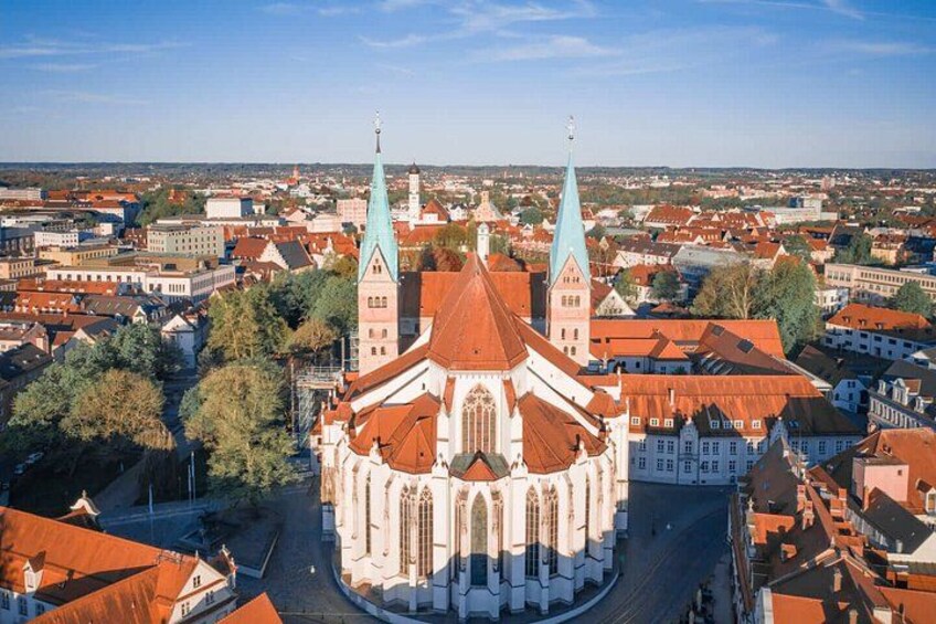 A cathedral with two spires, surrounded by a cityscape with red-roofed buildings. 2