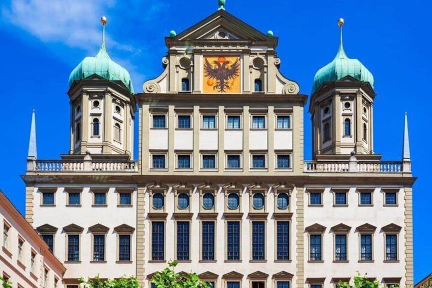 A historic building with two green domed towers and a central clock. 5